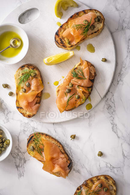 Копченый лосось кростини с каперсами, укропом, оливковым маслом и лимоном — стоковое фото