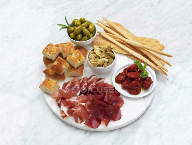 Ассортимент различных закусок с оливками и травами на белом фоне — стоковое фото