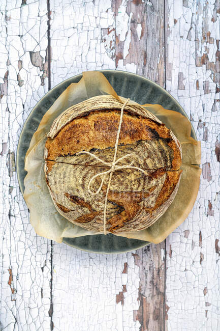 Sourdough loaf tied with twine on a rustic background — Stock Photo