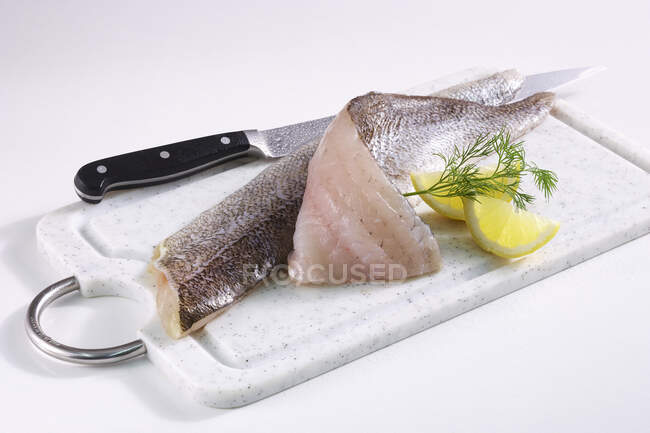 Zander fillets with skin on a board with a knife, lemon and dill — Stock Photo