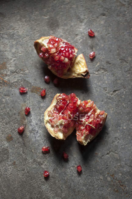 Crushed Pomegranate fruit with seeds on concrete surface — Stock Photo