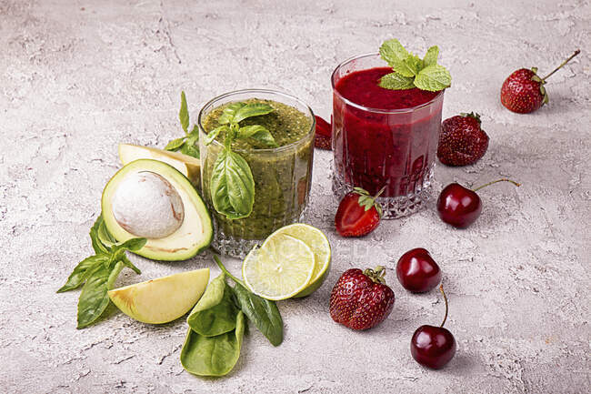 Green and red smoothie of strawberry, sweet cherry, avocado, spinach, basil, lime, green apple — Stock Photo
