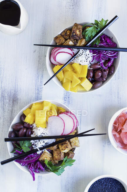 Веганська миска з рисом басматі, манго, смаженим тофу, фіолетовою капустою, редькою, оливками, маринованим імбиром та чорним кунжутом — стокове фото