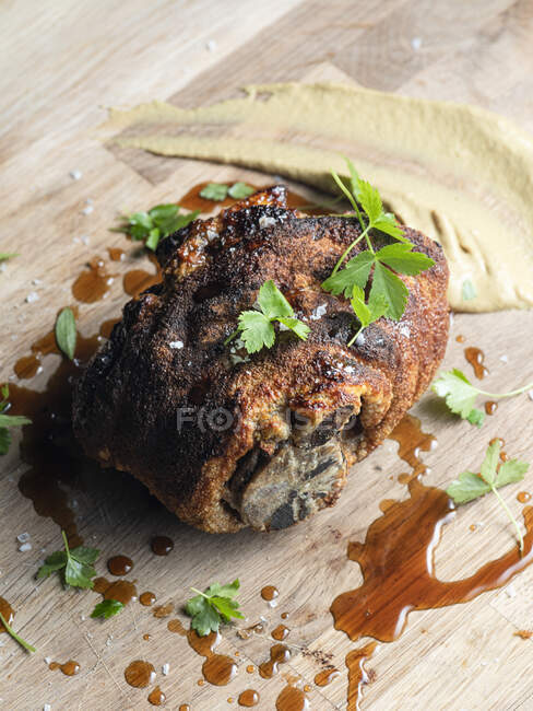 Nudillo de cerdo con mostaza y perejil sobre superficie de madera - foto de stock