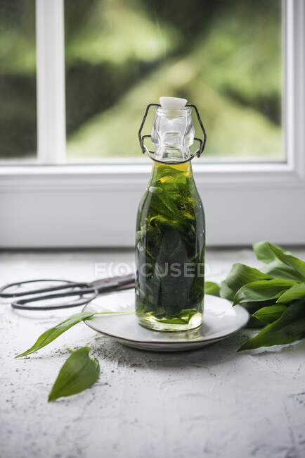 Close-up de delicioso óleo de alho selvagem em uma garrafa de vidro — Fotografia de Stock
