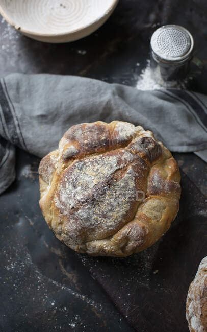 Sourdough loaf with gray cloth and flour on table — Stock Photo
