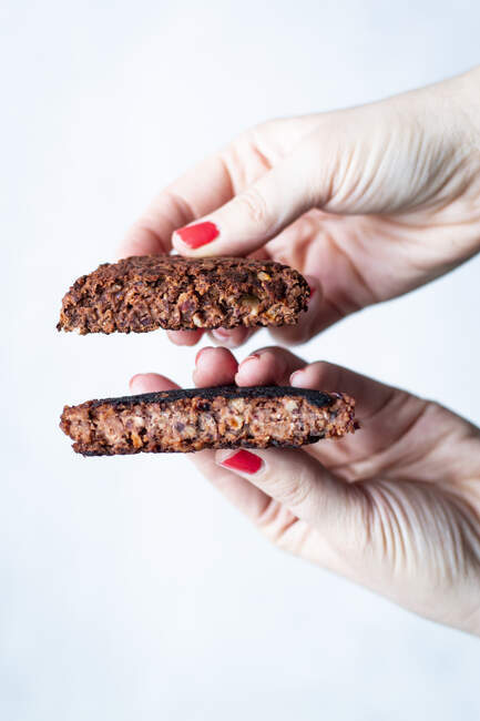 Hands holding a vegetarian burger pattie made from black beans — Stock Photo
