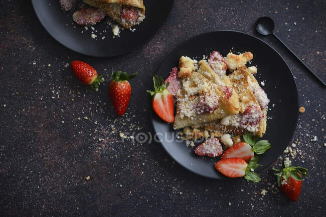 Gebackene Pfannkuchen mit Erdbeeren auf schwarzem Teller Erdbeeren — Stockfoto