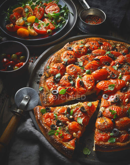A tomato pizza with olives and pine nuts — Stock Photo