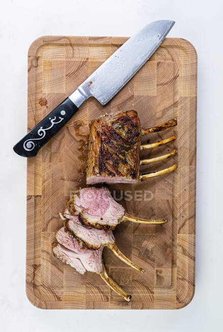 Rack de cordeiro em uma tábua de corte com uma faca — Fotografia de Stock