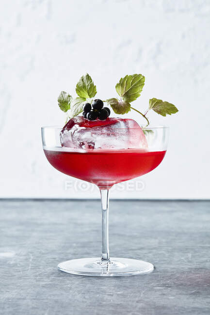 Huckleberry Cocktail mit Eisfelsen, Beeren und grünen Blättern im Glas — Stockfoto