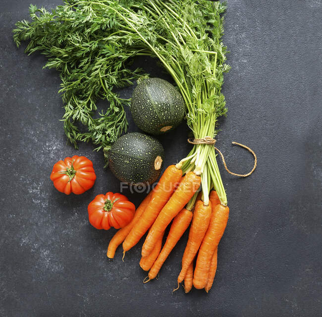 Zanahorias, tomates y calabacines sobre fondo negro - foto de stock