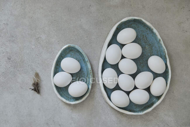 Egg-shaped ceramic plates with white eggs — Stock Photo