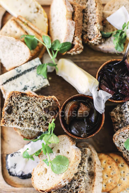 Cheese platter with bread, pickles and herbs — Stock Photo