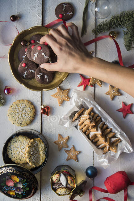 Various Christmas cookies, female hand taking dessert - foto de stock