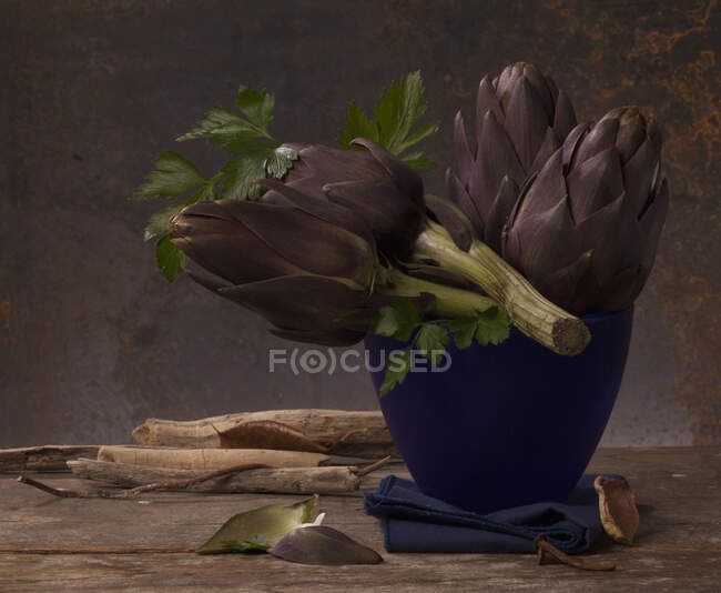 Artischocken und Petersilie in einer blauen Vase — Stockfoto