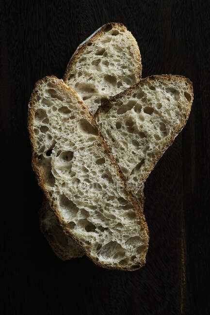 Massa azeda fatias de pão no fundo preto — Fotografia de Stock