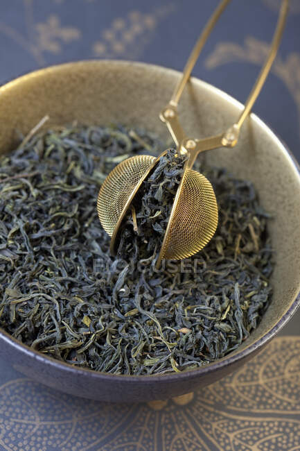 Mao Feng, green tea from China with a tea strainer in a bowl — Stock Photo