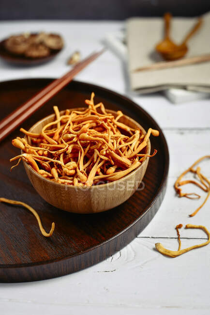 Fried caterpillar mushrooms in wooden bowl with chopsticks — Stock Photo