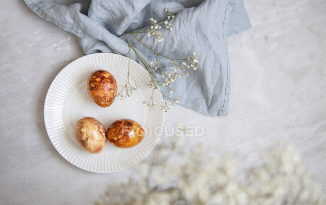Uova di Pasqua nel cestino, naturalmente tinte con pelli di cipolla, fiori ed erbe su sfondo di marmo — Foto stock