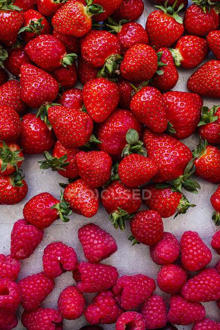 Fresh strawberries and raspberries on stone surface — Stock Photo