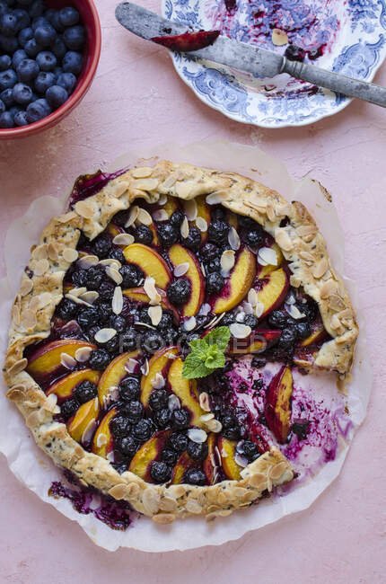 Peaches and blueberries pie with missing piece served on table — Stock Photo