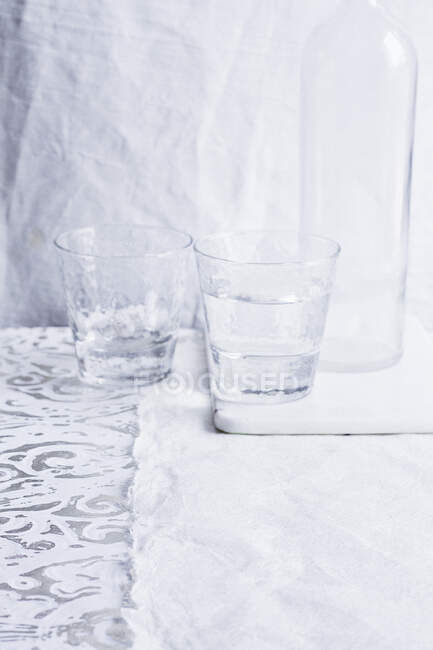 Dois copos de água e garrafa no fundo rosa — Fotografia de Stock