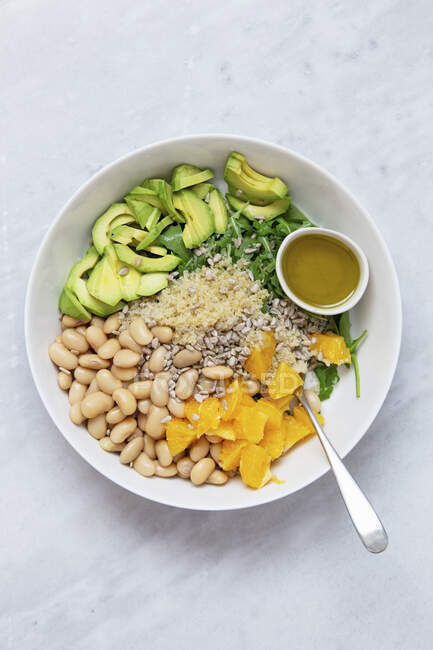 Vegetarian salad with avocado, white beans, arugula, spinach, sunflower seeds, orange and quinoa — Stock Photo