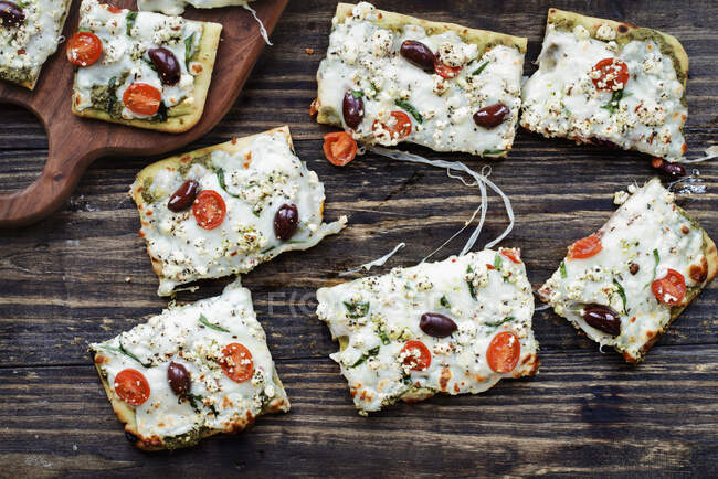 Художня піца з сиром моцарелла, свіжими помідорами, козячим сиром, шпинатом, оливками каламата та песто — стокове фото