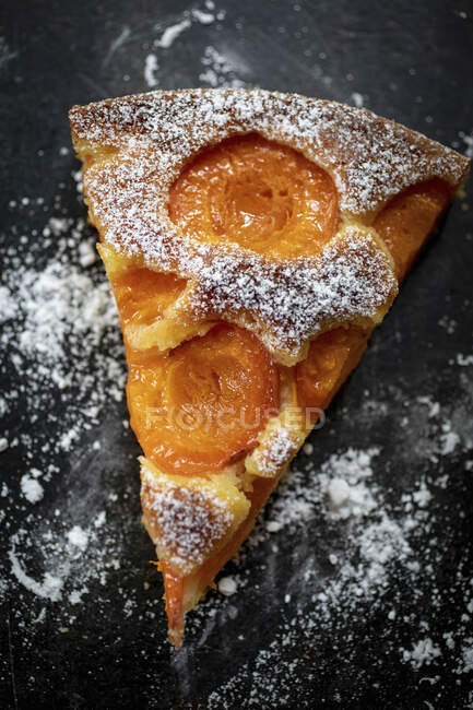 A slice of apricot cake dusted with icing sugar — Stock Photo