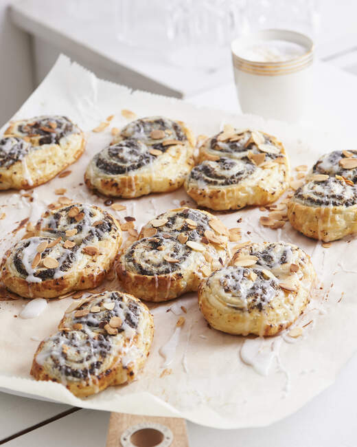 Poppy seed puff pastry buns with icing and flaked almonds - foto de stock