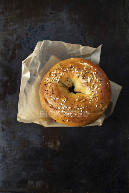 A sesame seed bagel on a piece of paper — Stock Photo