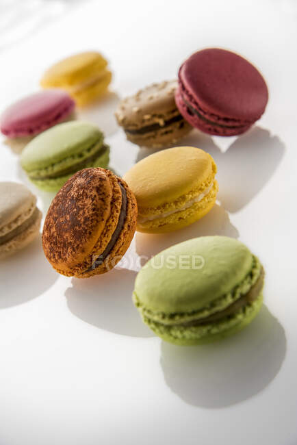 Different colorful macarons on white glass surface — Stock Photo