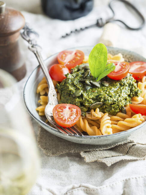 Vegan green pesto with dried tomatoes, served with red lentil fussili pasta — Stock Photo
