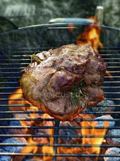 Gigot d'agneau sur grille barbecue avec feu — Photo de stock