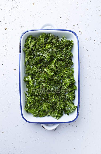Raw kale with olive oil and spices for kale chips — Stock Photo