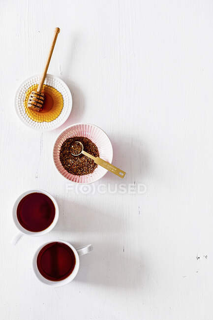 Tea in cups, honey and flax seeds in bowls — Stock Photo