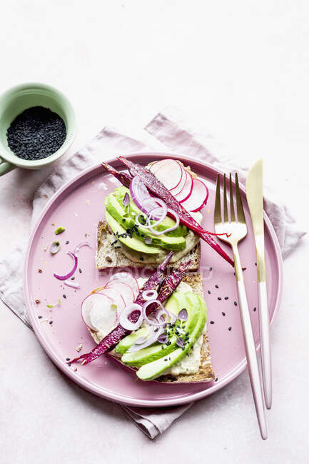 Hummus sandwich with avocado, radish, carrots, onion, black sesame seeds — Stock Photo