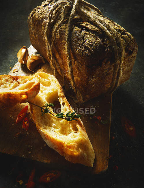 Ciabatta-Scheiben und ein rustikales Brot auf einem Holzbrett — Stockfoto