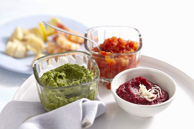 Bowls of various sauces for a fish fondue (exotic chutney, beetroot and horseradish dip, rocket and nut pesto) — Stock Photo