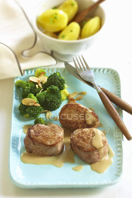Pork medallions with broccoli and flaked almonds — Stock Photo