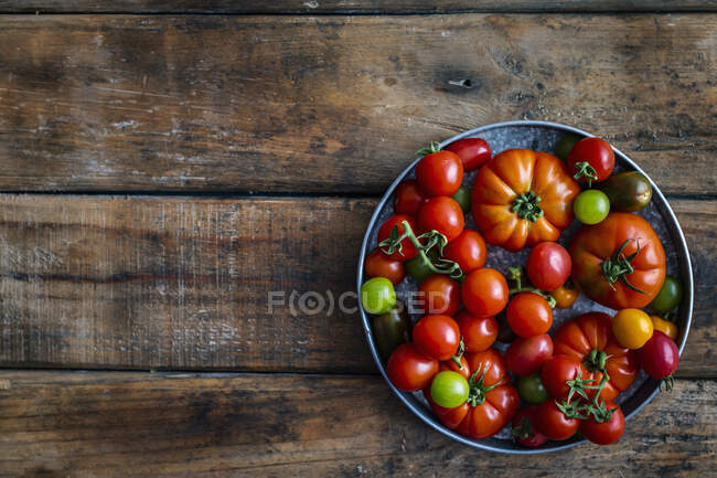 Свіжі помідори в мисці на дерев'яному фоні. вид зверху . — стокове фото