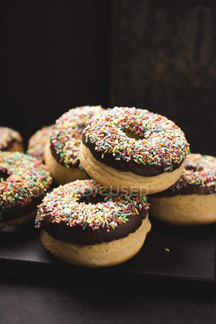 Oven-baked vegan donuts with dark chocolate icing and colorful sprinkles — Stock Photo