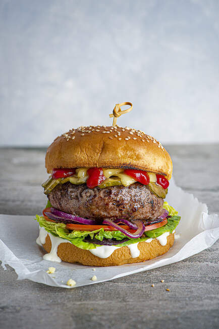 Chesburger with pickled cucumber, tomatoes, onion, salad, lettuce, mayo and ketchup — Stock Photo