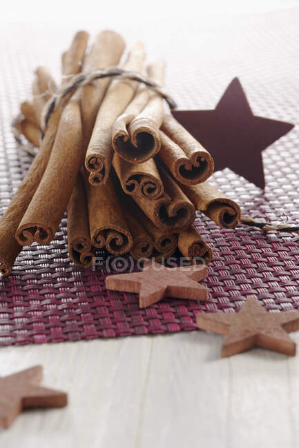 Палички кориці та дерев'яні зірки на фіолетовій поверхні — стокове фото