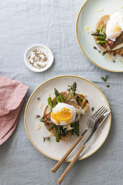 Poached egg on toast with asparagus, ham, parmesan cheese and thyme — Stock Photo