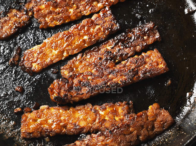 Tempeh bacon strips in cast-iron skillet — Stock Photo