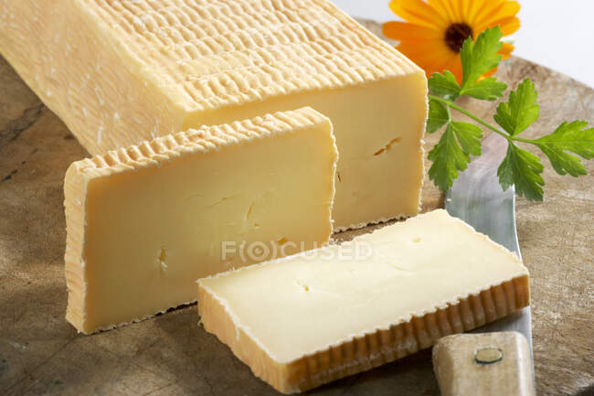 Organic soft cheese with flower and knife on wooden board — Stock Photo