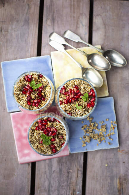 Granola with yoghurt and pomegranate seeds in bowls — Stock Photo