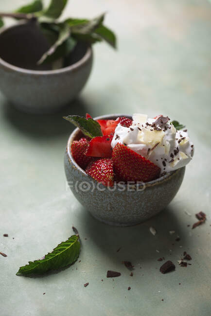 Strawberries with cream, mint, white and dark chocolate in bowl — Stock Photo